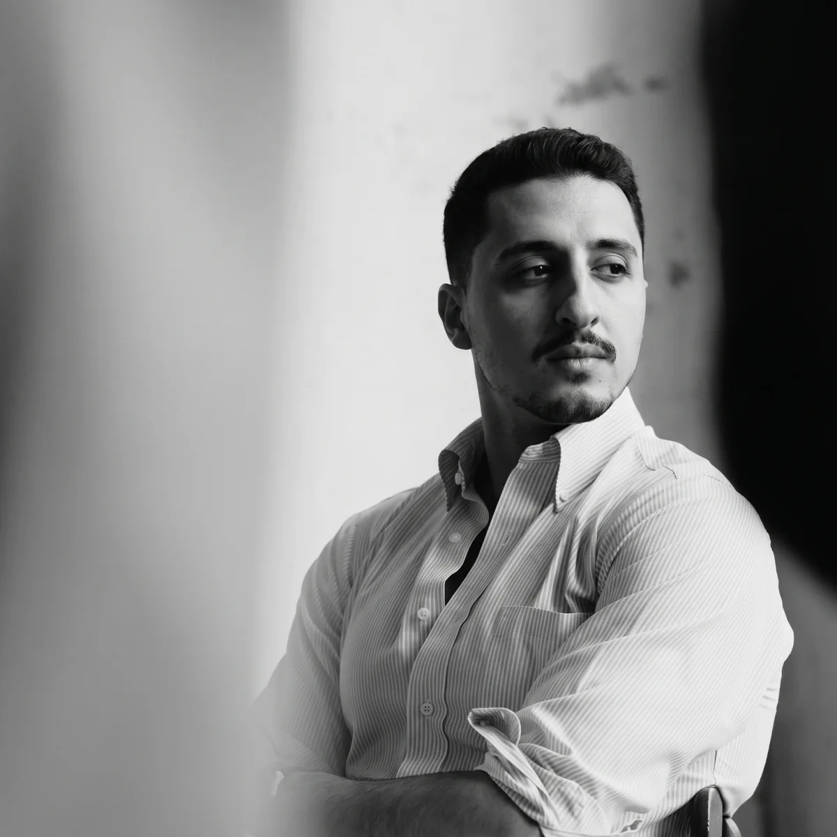Black-and-white portrait of Arch. Amr Eissa, founder of EISKAL, seated with arms folded and looking to the side
